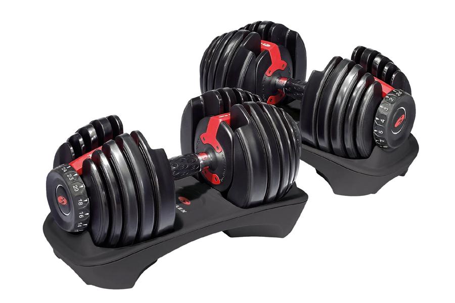 Pair of black adjustable dumbbells with red handles and weight plates on matching black stand with white background