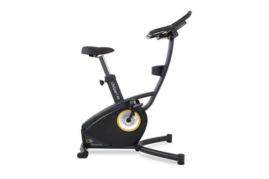 Black upright exercise bike with yellow and gray resistance wheel, black padded seat and handlebars, displayed on white backg