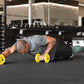 Man in plank position holding yellow dumbbells in modern gym setting