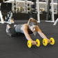 Woman performing plank exercise with yellow SKLZ COREwheels on black gym floor
