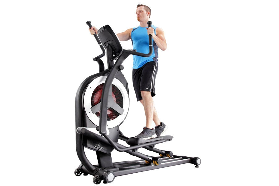 Man exercising on black and gray California Fitness elliptical machine with red wheel, wearing blue tank top and black shorts
