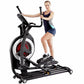 Black and white elliptical machine with red wheel display, model shown with woman in dark athletic top and shorts during demo