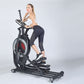 Woman using black elliptical machine with red wheel and digital display on white background