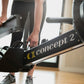 Concept2 RowErg indoor rowing machine with black frame and gold lettering, person using equipment with hands on handlebar