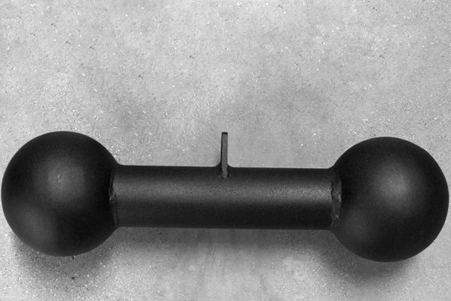 Black dumbbell-shaped pull-up bar attachment with spherical ends and cylindrical bar, flat lay on gray background