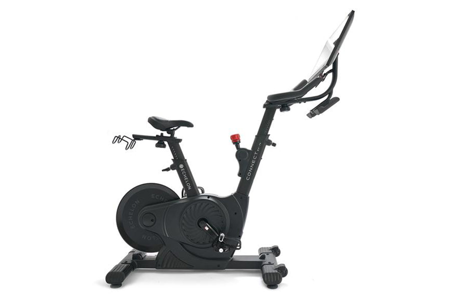 Black upright exercise bike with digital display, adjustable handlebars, padded seat, and weighted flywheel, on white backgro