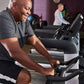 Man in gray t-shirt and black shorts using black Echelon Connect stationary bike with digital screen in gym setting