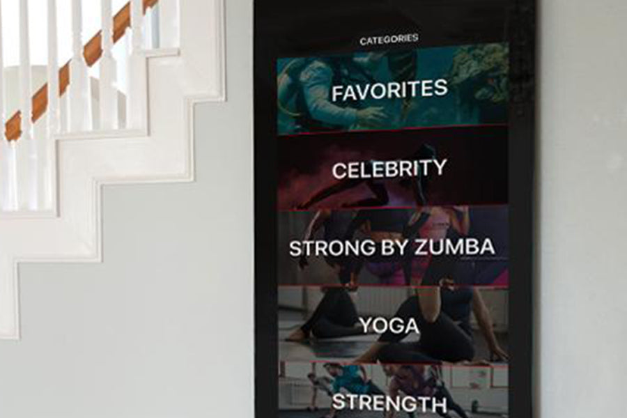 Echelon Reflect Touch 50 smart fitness mirror displaying categories including Favorites, Celebrity, Strong by Zumba, Yoga, an
