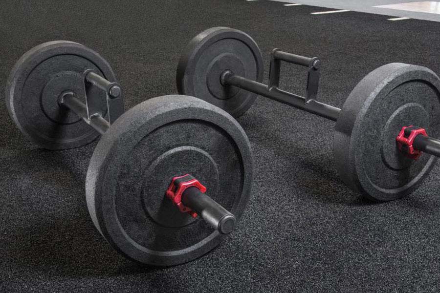 Set of black cast iron dumbbells with red handles on gray gym floor
