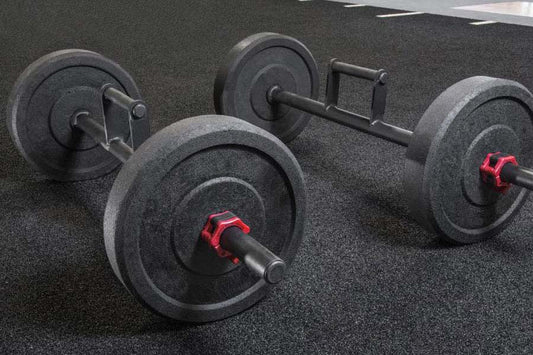 Set of black cast iron dumbbells with red handles on gray gym floor