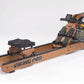 A Viking Pro indoor rowing machine with a wooden frame and black accents, featuring a water tank and black seat.