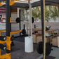 Yellow and black pull up attachment mounted on power rack with barbell in gym setting