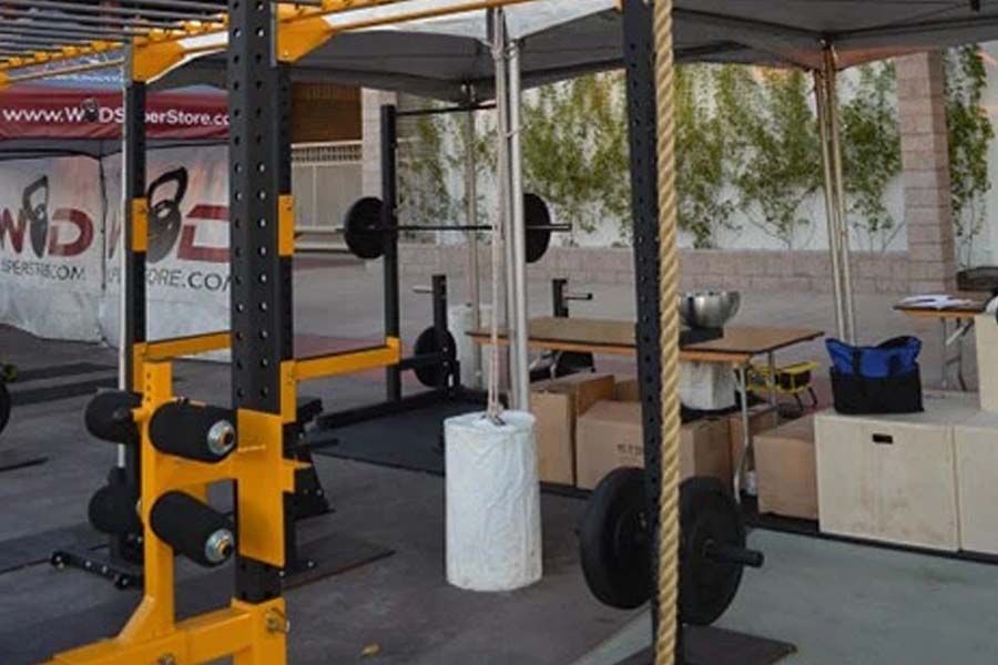 Yellow and black pull up attachment mounted on power rack with barbell in gym setting