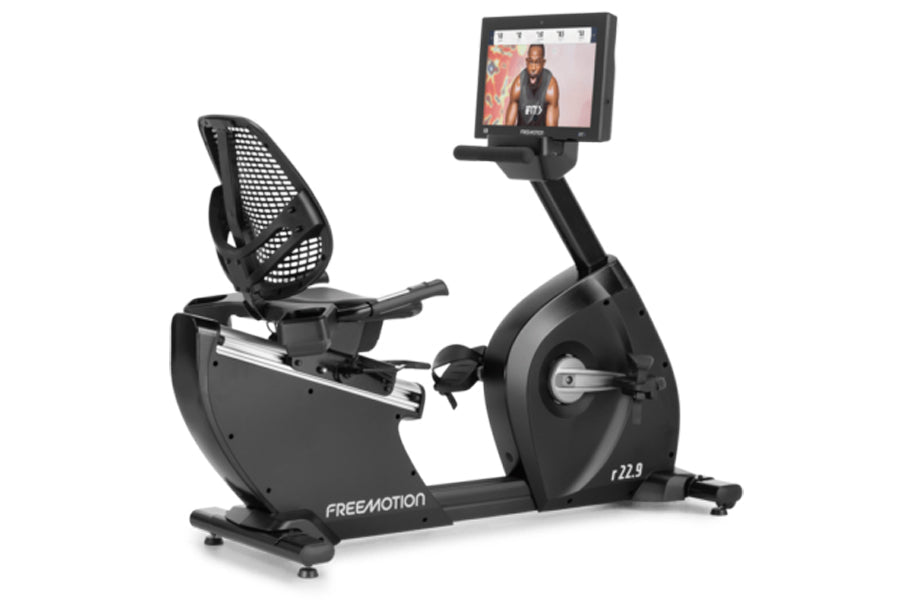 Freemotion r22.9 recumbent exercise bike with black frame, mesh backrest, and integrated touchscreen display showing workout 