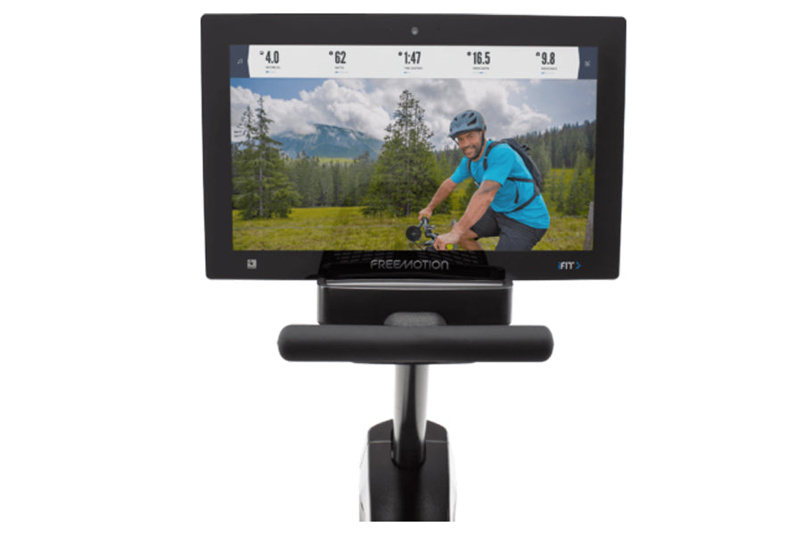 Freemotion R22.9 recumbent exercise bike with black frame and console displaying cycling workout video on white background