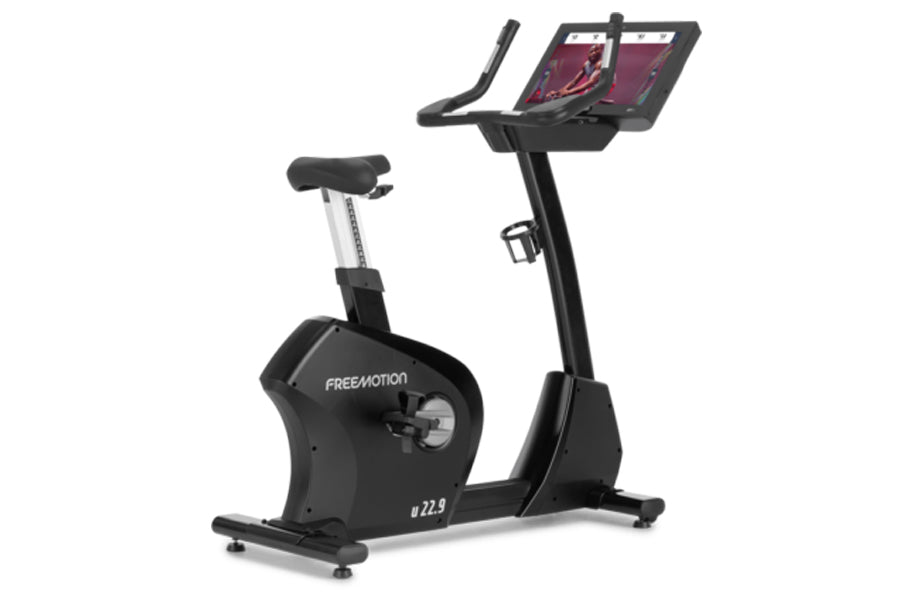 Freemotion u22.9 black upright exercise bike with dual tablet holder and adjustable seat on white background
