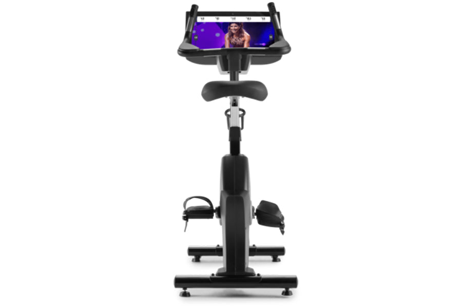 Black upright exercise bike with padded seat, handlebars, and adjustable smartphone holder displaying workout app on white ba