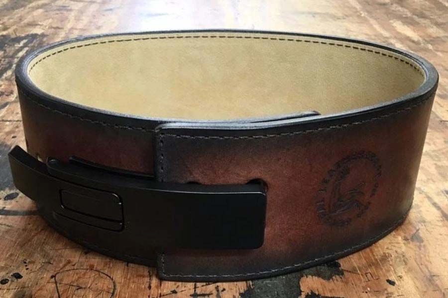 Brown leather weightlifting belt with cream suede lining and black metal buckle closure, displayed on wooden surface