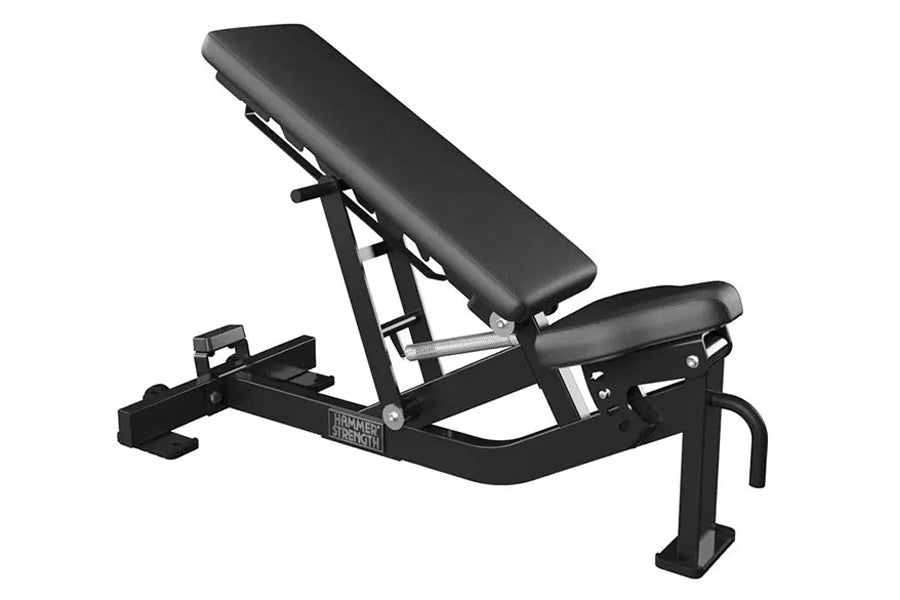Hammer Strength black adjustable weight bench with incline backrest and leg extension attachment on white background