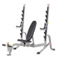 Multi-purpose squat rack with silver frame, black padded seat, dual weight bar holders, and adjustable safety arms on white b