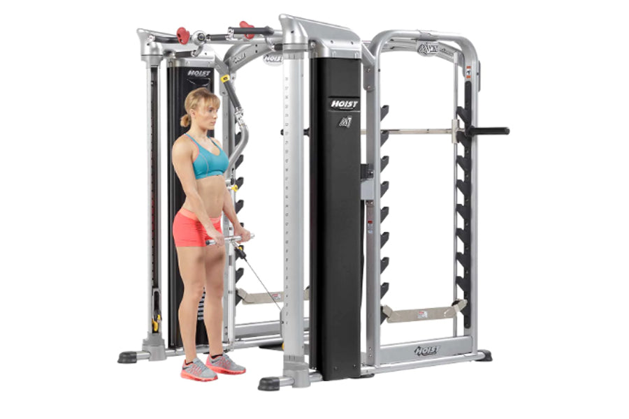 Hoist Mi7Smith functional training system with silver frame and black panels, woman demonstrating pec fly exercise on white b
