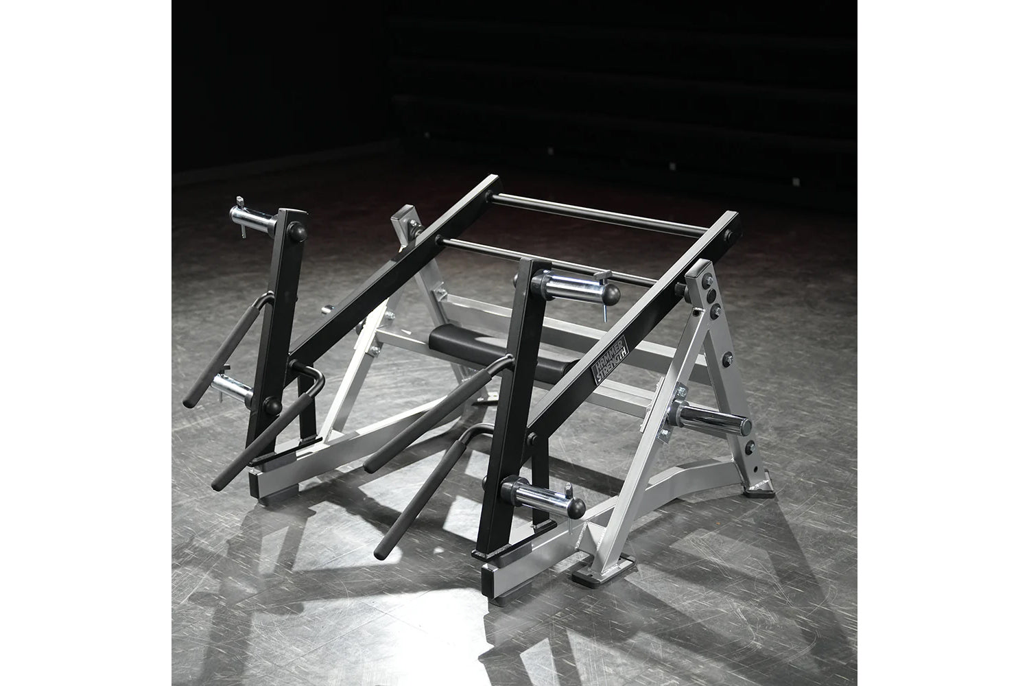 Hammer Strength Ground Base Multi-Squat Machine with black uprights and silver steel frame on dark textured floor