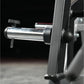 Hammer Strength ground base multi-squat machine with polished steel bar and black frame on black background, detail view