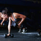Athletic woman in black sports bra performing dumbbell push-up exercise with hex dumbbells in gym setting
