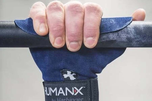 Navy blue wrist-wrap pull-up grips with black padding worn by hand gripping bar, showing grip detail