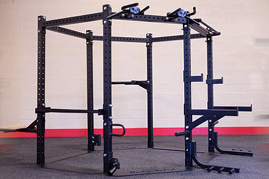 Black steel hexagonal squat rack with blue attachment brackets and pull-up bars, on gym flooring