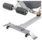 Gray stationary ab bench with black padded footrest rollers, white foot platform, and casters, shown from angled view on whit