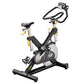 Black and silver indoor exercise bike with yellow accents, digital display on handlebars, and wide base on white background