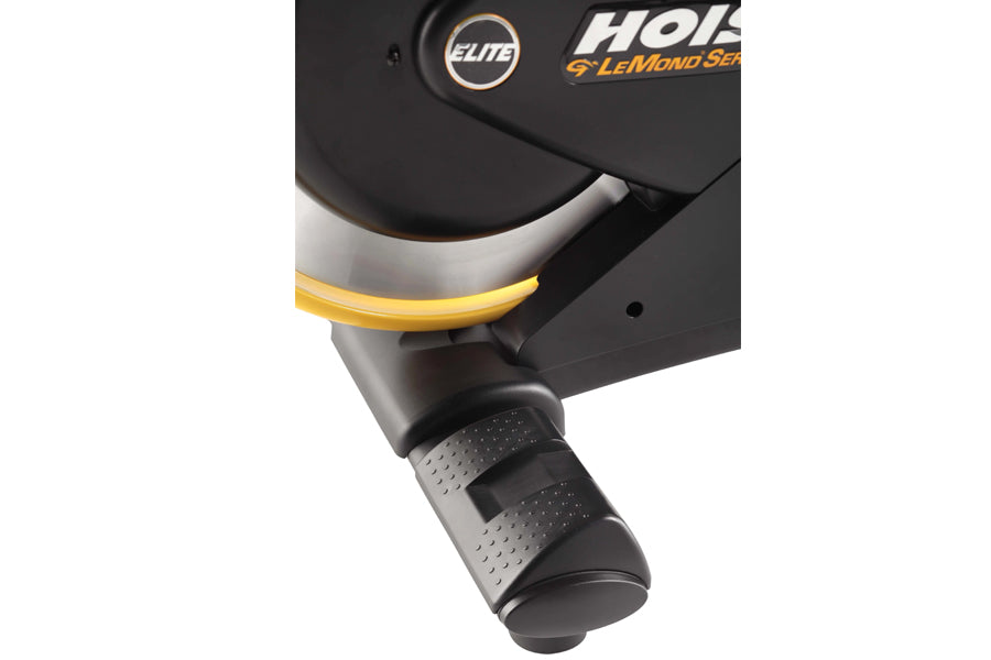 Hoist Lemond Series Elite stationary bike with black frame, yellow accent stripe, and textured gray foot pedal on white backg