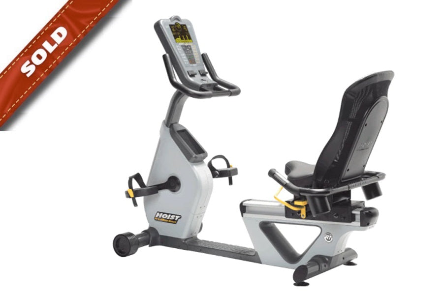 Hoist Lemond RT recumbent exercise bike with white frame, gray seat, digital display console, and black foot pedals on white 