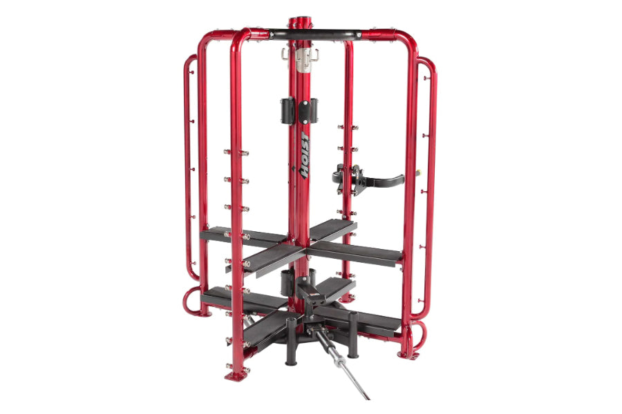 Red and black multi-station gym equipment with rounded frame, black foot platforms, and leg press attachment on white backgro