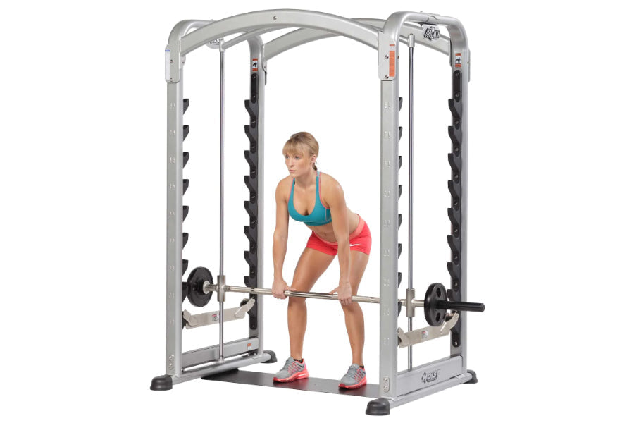 Silver and black dual action smith machine with woman demonstrating exercise in teal sports bra and pink shorts
