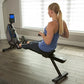 Woman using black Horizon Oxford 6 rowing machine with digital display, worn in home gym setting