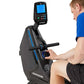 Man in blue shirt using black and blue Horizon stationary exercise bike with digital display on white background