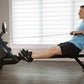 Man in blue t-shirt and black shorts using Horizon Oxford 6 black rowing machine in home gym with large windows