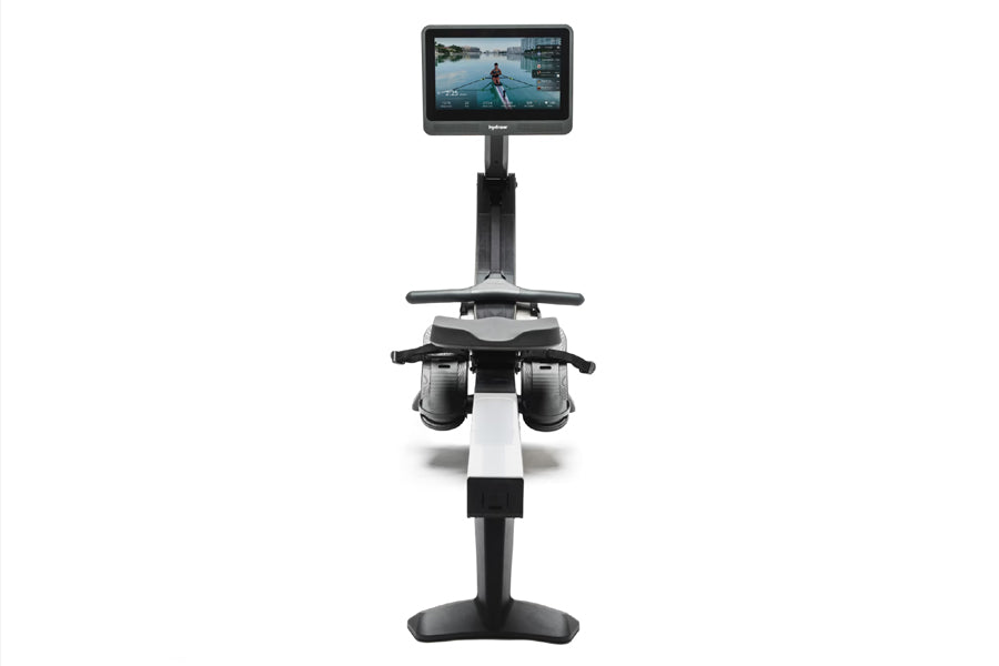 Hydrow Wave rowing machine with digital display screen showing workout video, black and white frame with pedal straps on whit