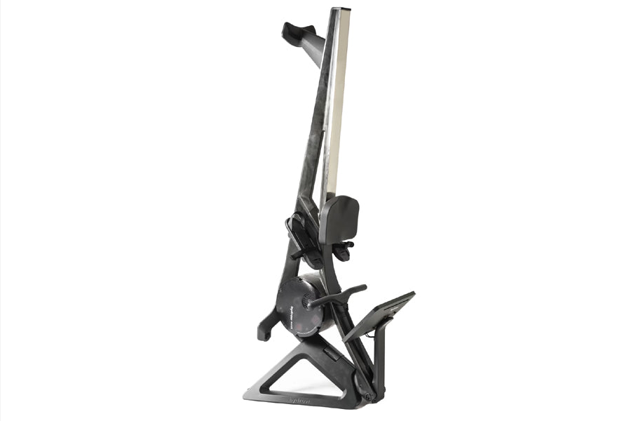 Black and silver Hydrow Wave rowing machine with tall vertical rail, footplate, and seat on white background