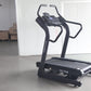 Black motorized treadmill with digital console display and curved handles, on concrete floor in warehouse setting