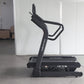 Black treadmill with curved running deck and dual handles labeled "CF IT8" on concrete floor in warehouse setting