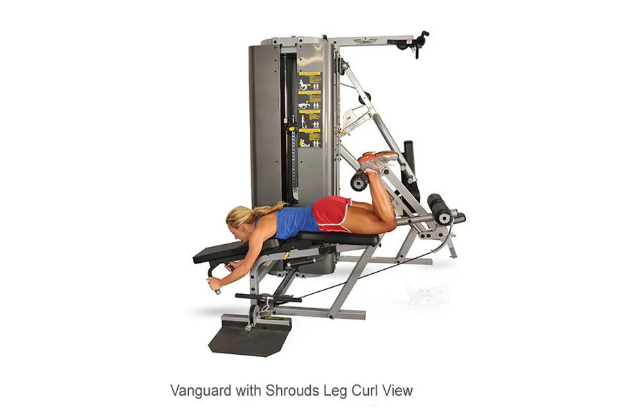 Person performing leg curl exercise on Inflight Vanguard 2-Stack multi-gym with gray metal frame and yellow weight stack