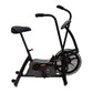Black upright air bike with padded seat, curved handlebars, large fan wheel, and digital display on white background
