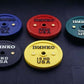 Ivanko color bumper plates in blue 20kg, red 25kg, teal 50kg, black 10kg, and yellow 15kg on dark textured floor