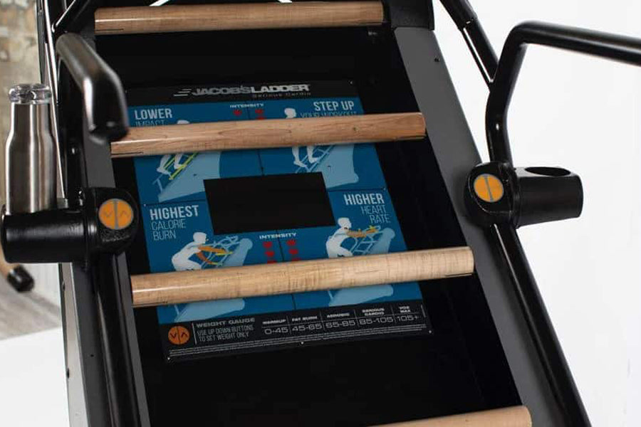 Jacobs Ladder X climbing machine with black metal frame, wooden rungs, and blue digital display panel showing workout metrics