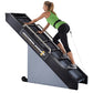 Woman in green sports bra and black leggings using black and gray Jacobs Ladder 2 climbing machine against white background