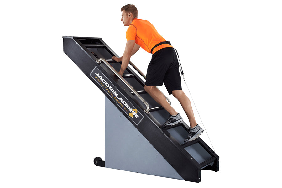 Man in orange shirt and black shorts climbing on black and gray Jacobs Ladder 2 exercise machine against white background