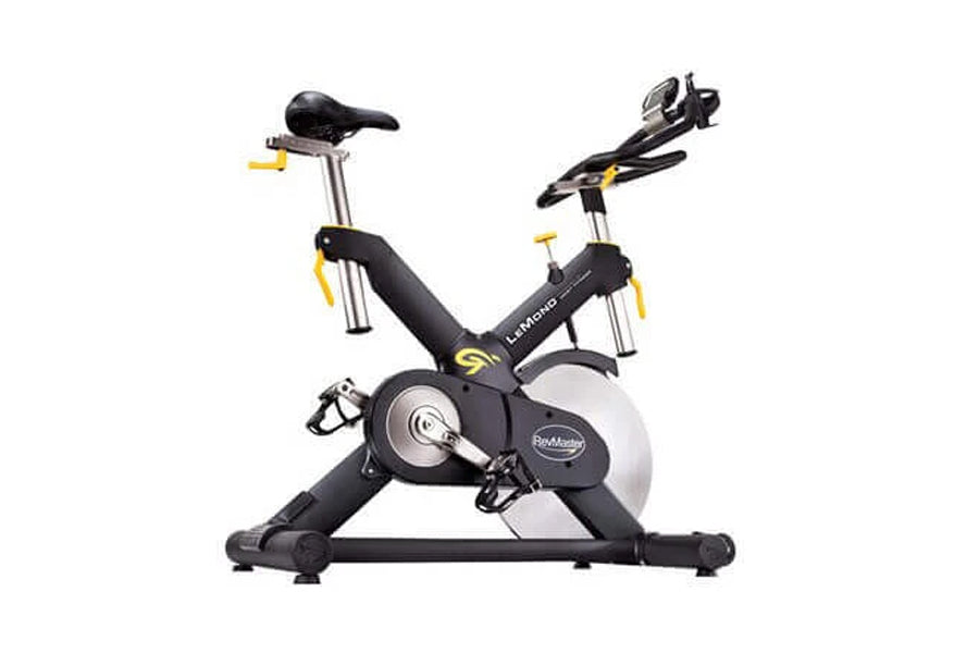 Black and silver stationary indoor cycling bike with yellow accents, adjustable seat and handlebars, digital console, on whit